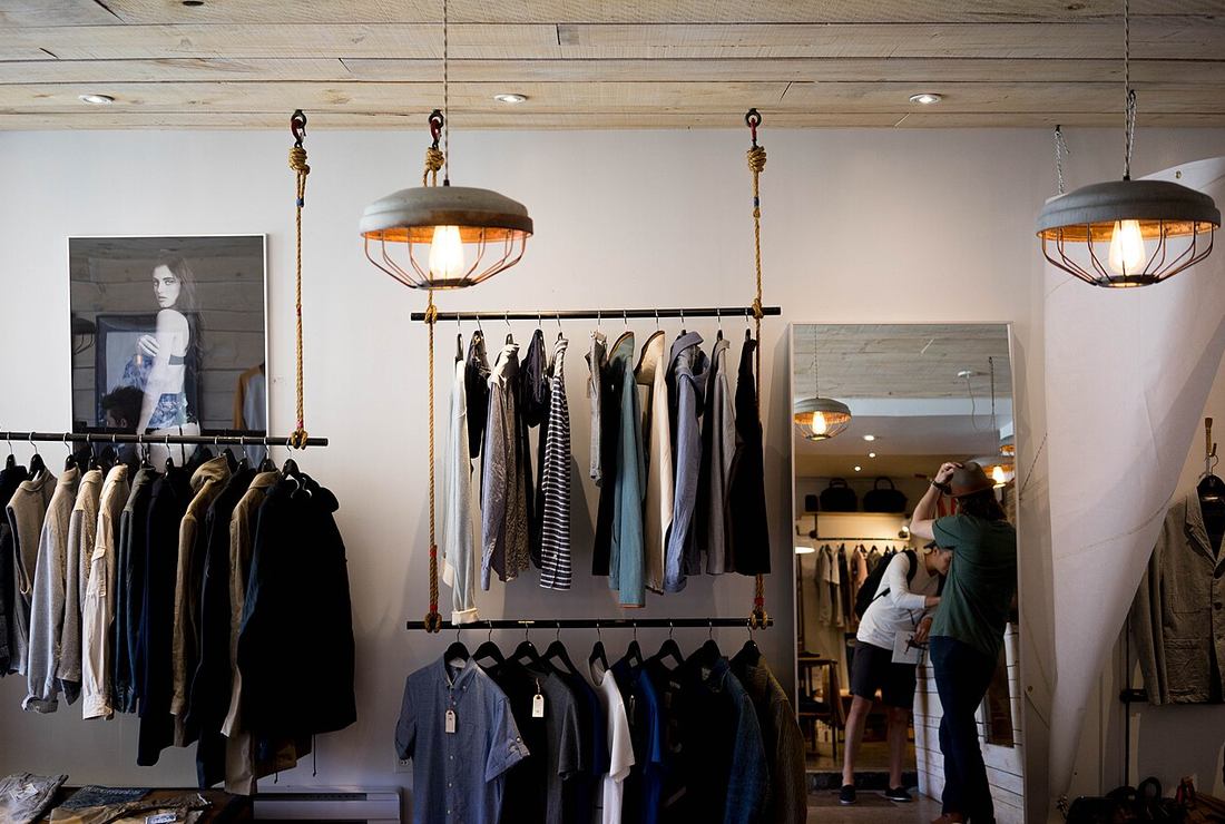 Interior de tienda de ropa organizada con prendas en percheros